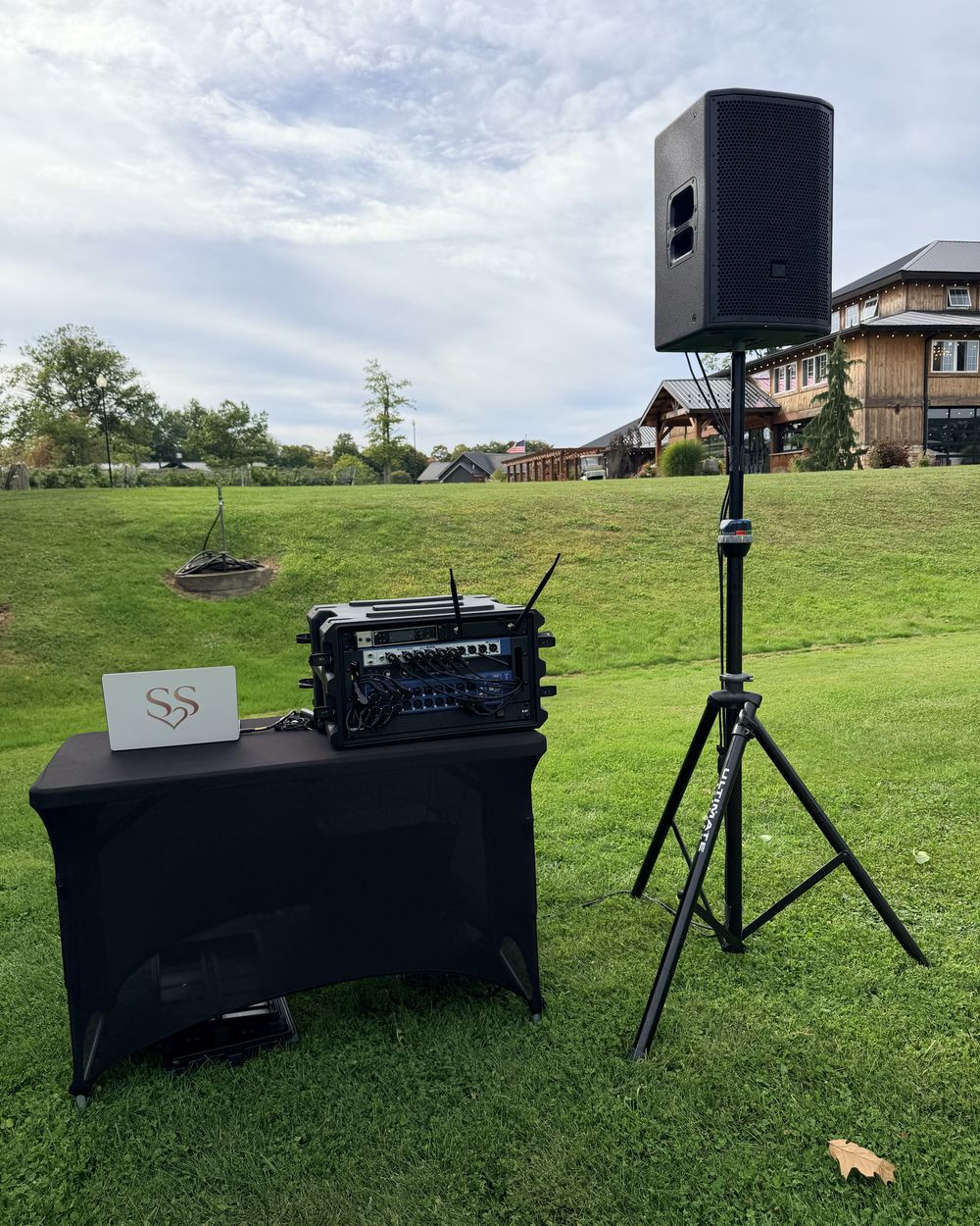 A speaker on a stand and a rack of sound equipment set up on the grass for a ceremony at Colloca Estate Winery