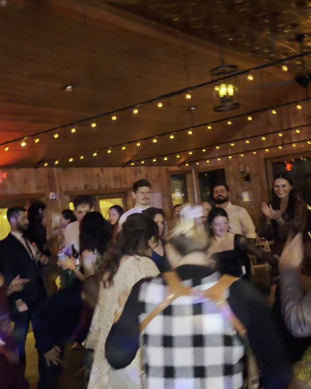 Guests dancing in the main building at New Park, under a timber ceiling strung with lights