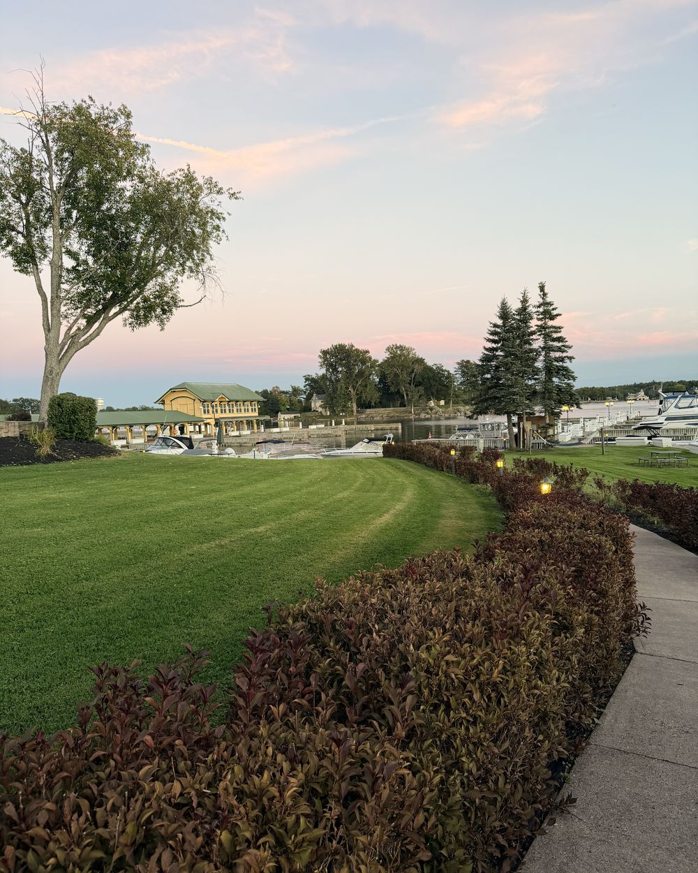 The lawn at the Thousand Islands Club running down to the boathouse and marina at sunset