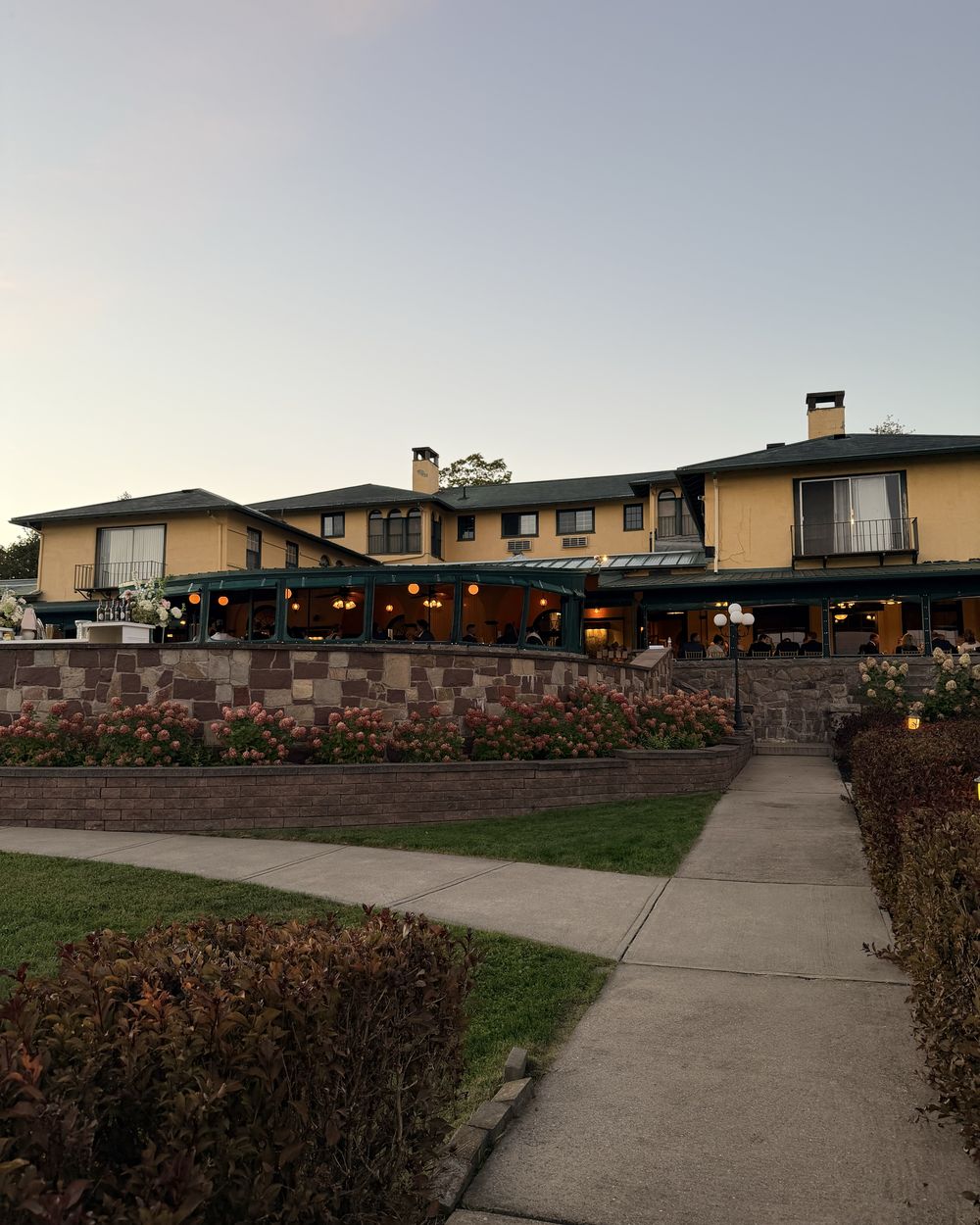 Guests at dinner on the covered porch of the Thousand Islands Club clubhouse at dusk
